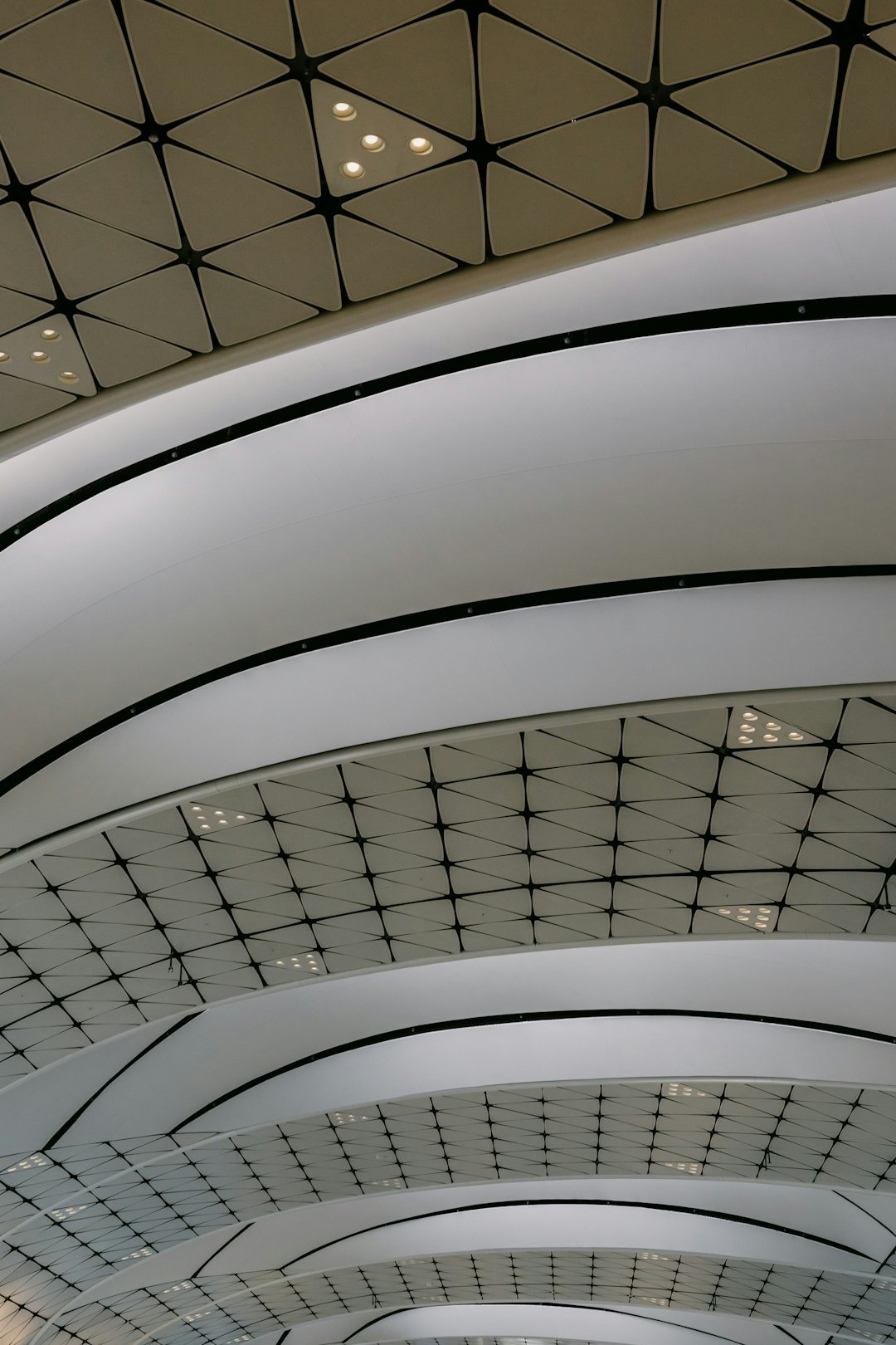 Modern ceiling with white undulating panels and grid lighting.